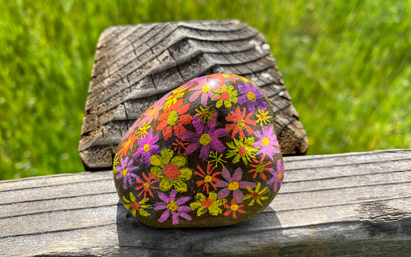 A painted rock on a fence crossbeam